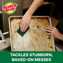 Green heavy-duty scour pad held in hand for scrubbing a baking tray