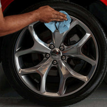 Blue multi-purpose paper towel wiping a car wheel rim