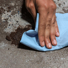Blue multi-purpose paper towel held in hand, wiping a dirty surface