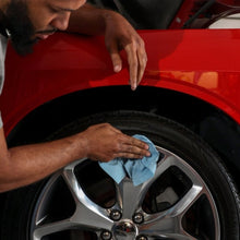 Blue shop towel wiping a car wheel rim, multi-purpose absorbent cleaning cloth