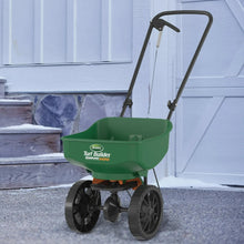 Green mini broadcast spreader with green hopper and four treaded wheels on a walkway