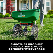 Green mini broadcast spreader dispensing granules onto grass with two front wheels