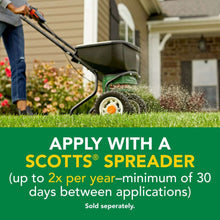 Lawn fertilizer application with a Scotts spreader dispensing granules onto grass