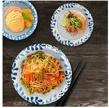 Paper soup and salad bowls with blue patterned rim, filled with food on a table.