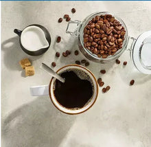 Whole coffee beans and cup of dark coffee with spoon, overhead view