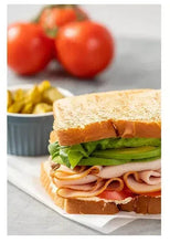 Sliced honey roasted turkey breast sandwich with greens and orange sauce on bread