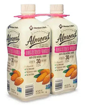 Three unsweetened vanilla almond milk bottles with front labels and pink caps