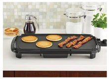 Black electric griddle with cooking surface and ridged front channel