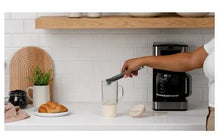 Glass tumbler with straw and handle being filled on countertop