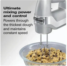 Silver electric hand mixer running beaters over cookie dough in bowl
