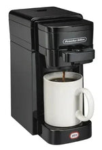 Black single-serve coffee maker brewing into white mug with visible coffee stream