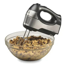 Stainless steel hand mixer with two beaters mixing batter in a glass bowl
