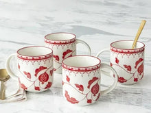Set of four off-white stoneware mugs with red leaf and berry pattern, with wooden stirrer
