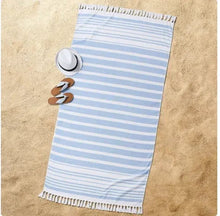 Blue and white striped beach towel with tassel fringe laid flat