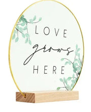 Translucent oval tabletop plaque with "LOVE" "HERE" lettering and solid wood base