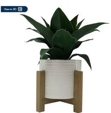 Artificial agave plant in white ceramic square pot on wood stand
