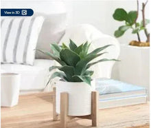 Artificial agave plant in white ceramic pot on light wood stand