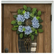 Hydrangea wreath with light blue flowers, green leaves, and small green filler blooms.