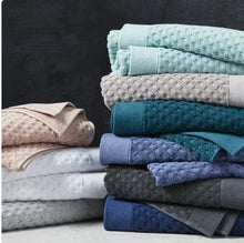 Stack of bath towels in assorted colors, showing textured weave and folded edges.