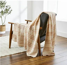 Striped gauze throw draped over a chair, copper-toned stripes on beige.
