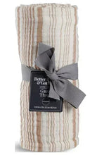 Striped gauze throw rolled and tied with a gray ribbon; copper-toned stripes.