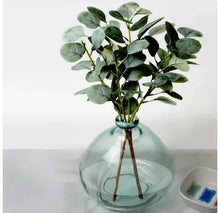 Artificial eucalyptus bouquet in teal blown-glass vase, rounded bubble style container