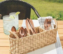 Beige oval rattan caddy with utensils and cutlery in woven compartments