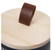 Wooden wick candle jar lid with embossed logo and wick tab, close-up