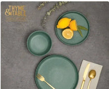 Caspian green stoneware plates and small bowls arranged for serving