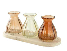 Three translucent glass bud vases on natural wood base tray, ribbed sides, amber and pale green