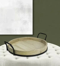 Round light wood tray with two black metal loop handles and shallow rim