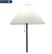 Pleated white fabric lampshade on matte black floor lamp with pull chain