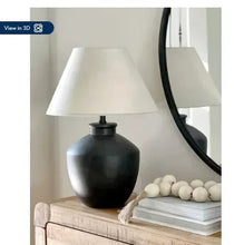 Black urn table lamp with white fabric shade and distressed textured base