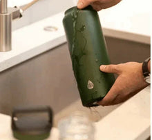 Green stainless steel water bottle tilted in hand, condensation visible