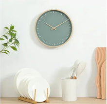 Round green analog wall clock with beige rim, white dot hour markers, and long hands