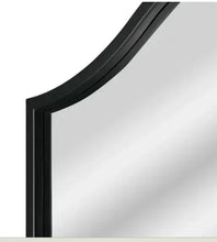 Black arched mirror frame close-up with smooth dark trim along the glass edge