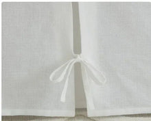 Bright white cotton bed skirt with three hanging bow ties at front corner