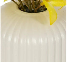 Ribbed off-white ceramic vase with artificial yellow forsythia blossoms