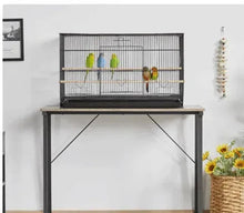 Black wire bird cage on a dark stand with front opening and interior perches.