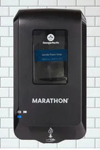 Black automated soap dispenser facing forward with dark window and blue indicator light