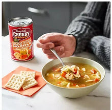 Chicken noodle soup in a bowl with crackers, next to a Chunky can