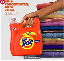 Orange Tide Original liquid laundry detergent jug held in hand above folded clothes