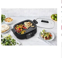 Matte black multi skillet with glass lid, handles, and sautéed vegetables.