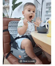Travel booster seat with zigzag cover; child seated and holding tray