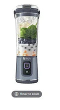 Portable blender with clear jar and denim-blue base, hinged handle, control panel.