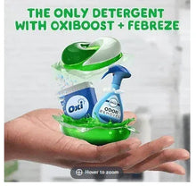 Hand holding green laundry detergent pacs with Oxi Boost and Febreze Odor Remover