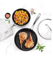 Nonstick black frying pans with chicken and vegetables, with utensils