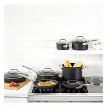 Hard-anodized nonstick cookware on stovetop: several black pots and pans