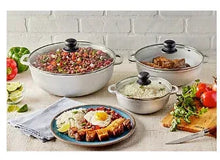 Round cast aluminum calderos with lids and black knobs, filled with food