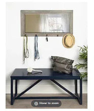 Wall-mounted rectangular mirror with wood frame and five metal hooks on bottom edge